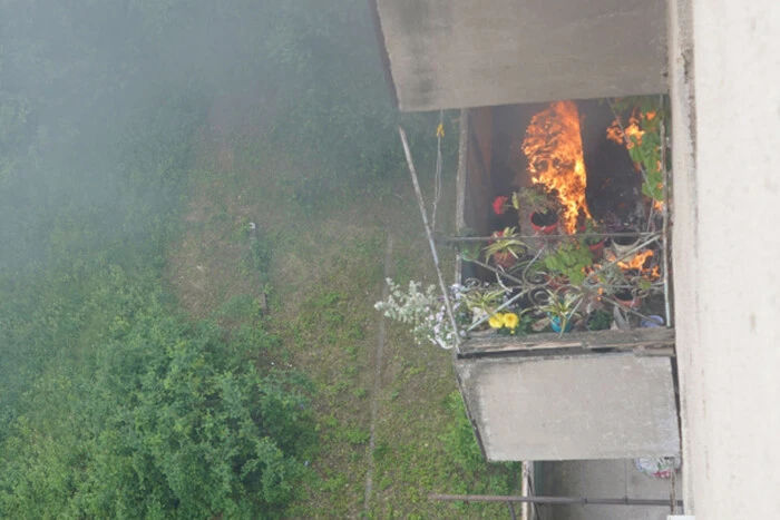 A woman throws a burning blanket onto the balcony